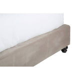 Mink brushed velvet fabric covers the base of a double bed, featuring a smooth texture and a subtle sheen. The bed has a low-profile design with a clean, modern aesthetic, and is supported by small black wheels for easy mobility. A white mattress and bedding are partially visible above the base