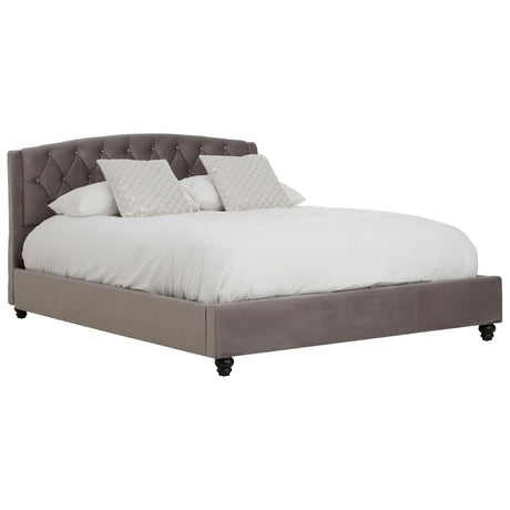 Grey velvet king bed with a tufted headboard, featuring two decorative pillows and a white comforter, resting on dark wooden legs