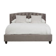 Grey velvet king bed with a tufted headboard, featuring two white decorative pillows and a white comforter, resting on dark wooden legs