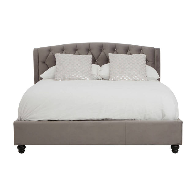 Grey velvet king bed with a tufted headboard, featuring two white decorative pillows and a white comforter, resting on dark wooden legs