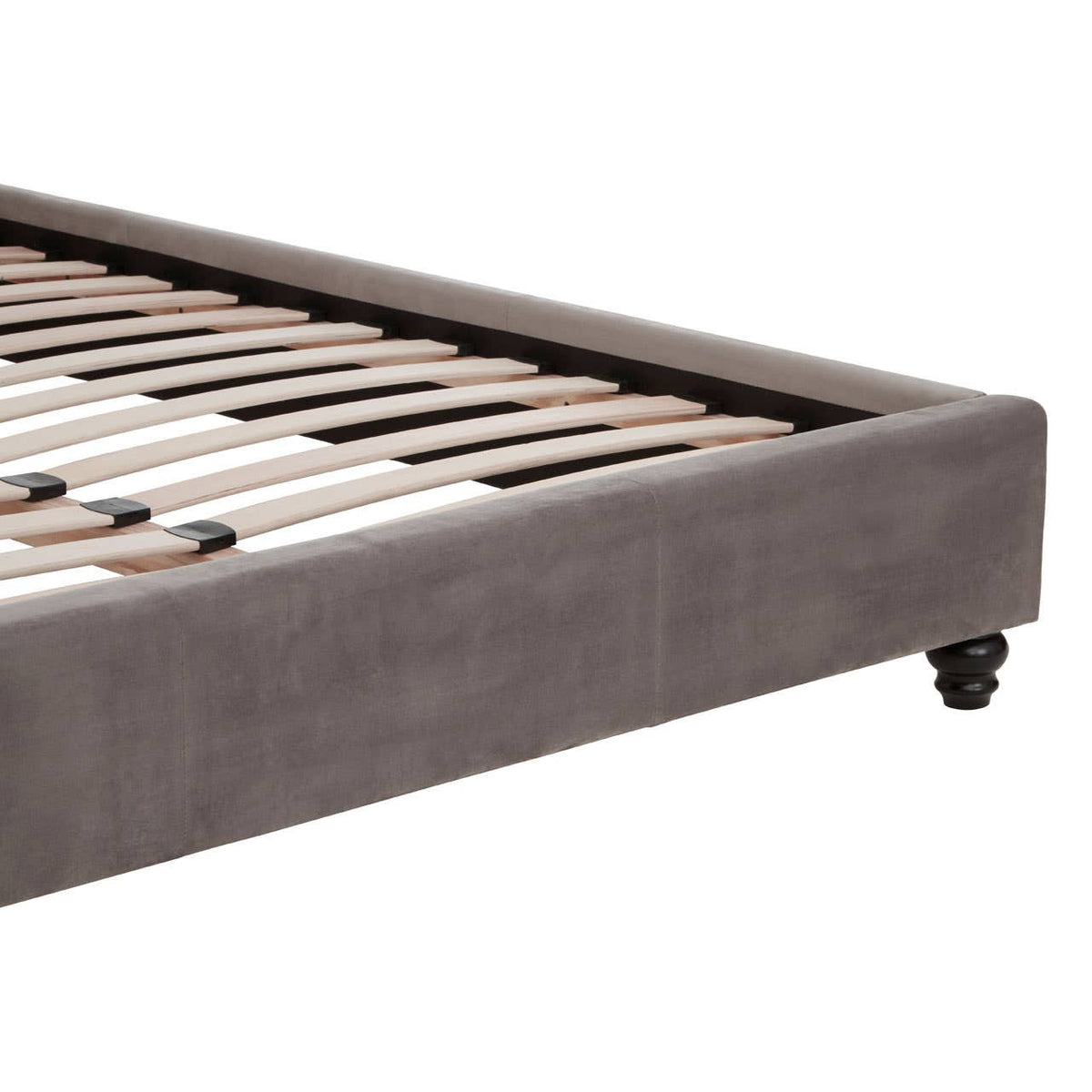 Grey velvet king bed with a low-profile design, featuring a sturdy wooden slat support system and smooth, rounded edges. The bed is mounted on small wheels for easy mobility