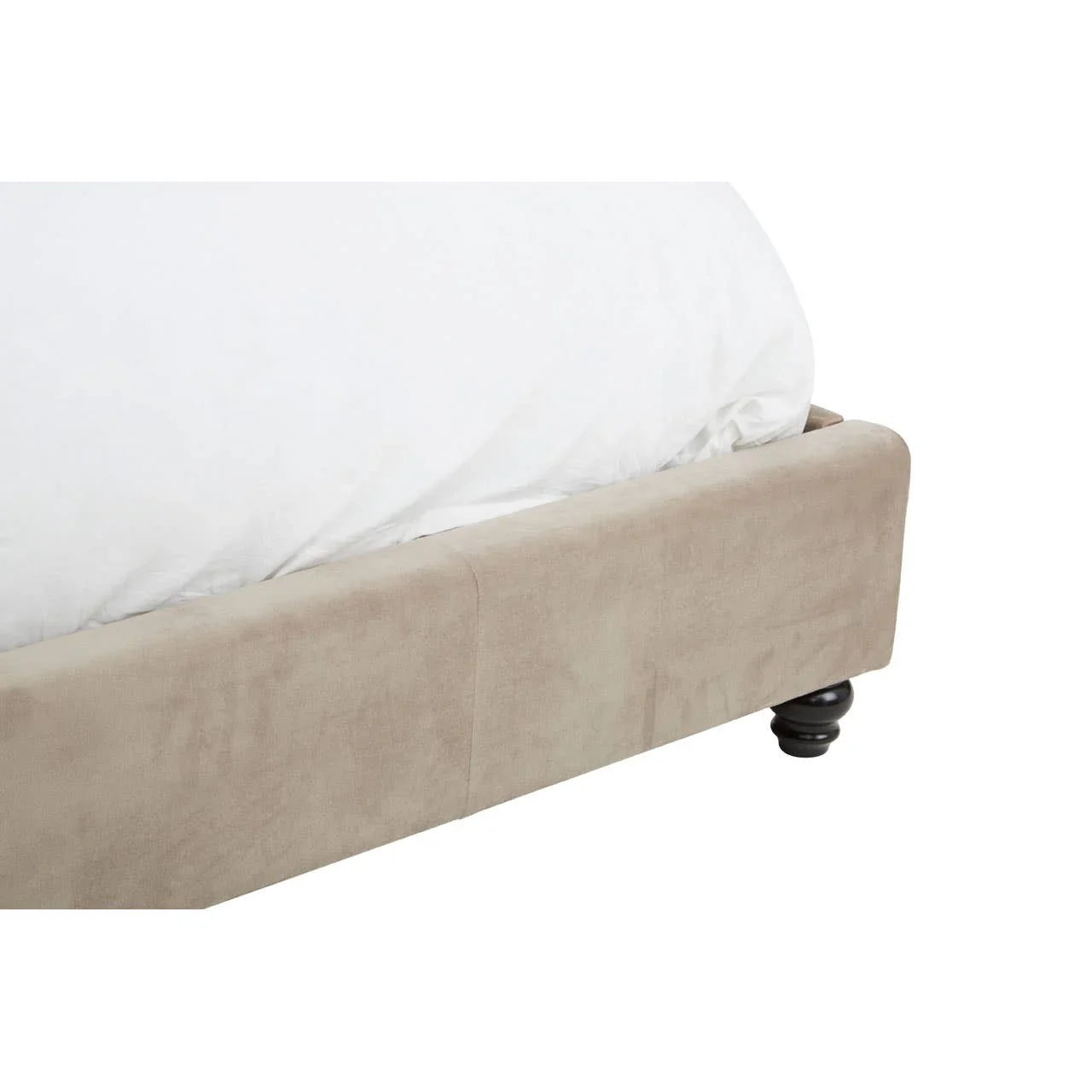 Beige upholstered bed frame corner with wooden turned leg and white bedding