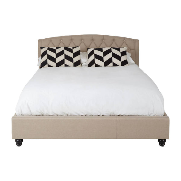 Beige king bed with a tufted headboard, featuring a white mattress and decorative black and white chevron-patterned pillows. The bed is supported by dark wooden legs