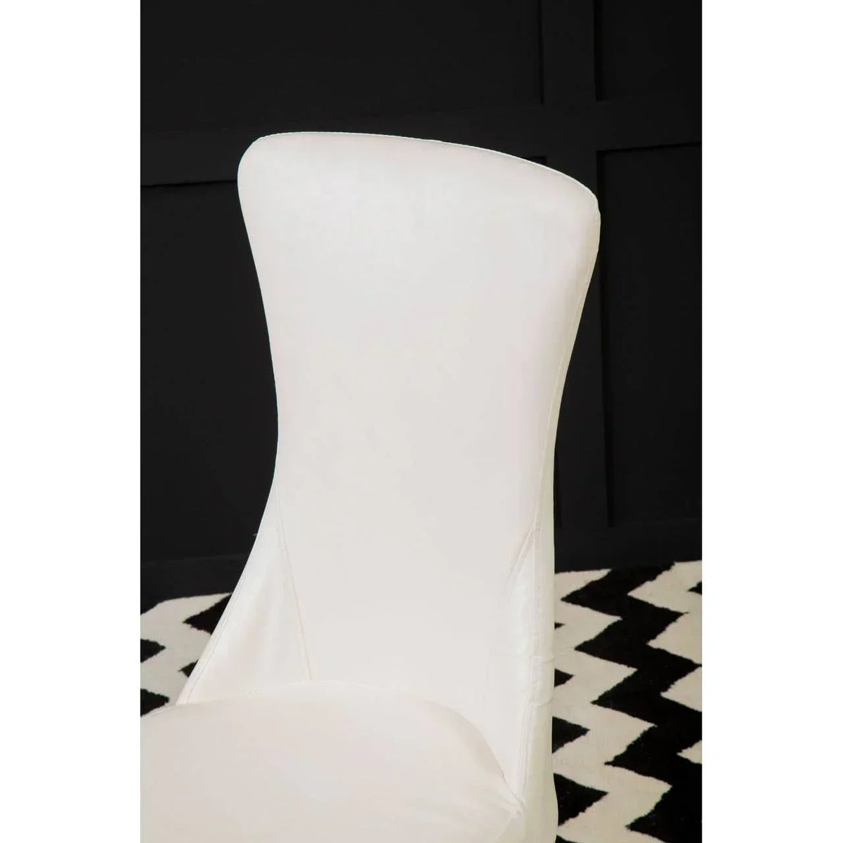 White leather dining chair with curved backrest on black and white chevron rug