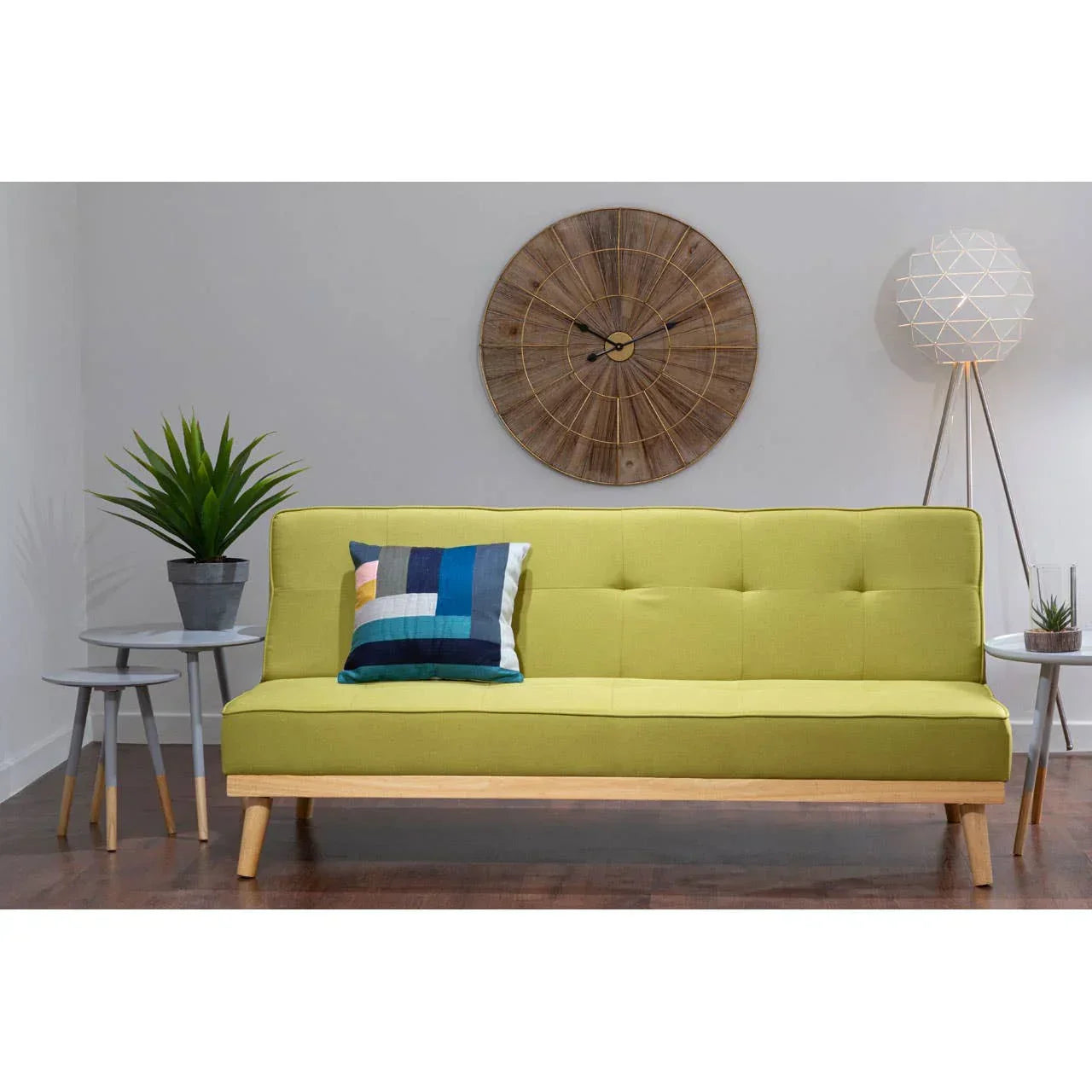 Modern yellow sofa with wooden base, accent pillow, round wall clock, and side tables