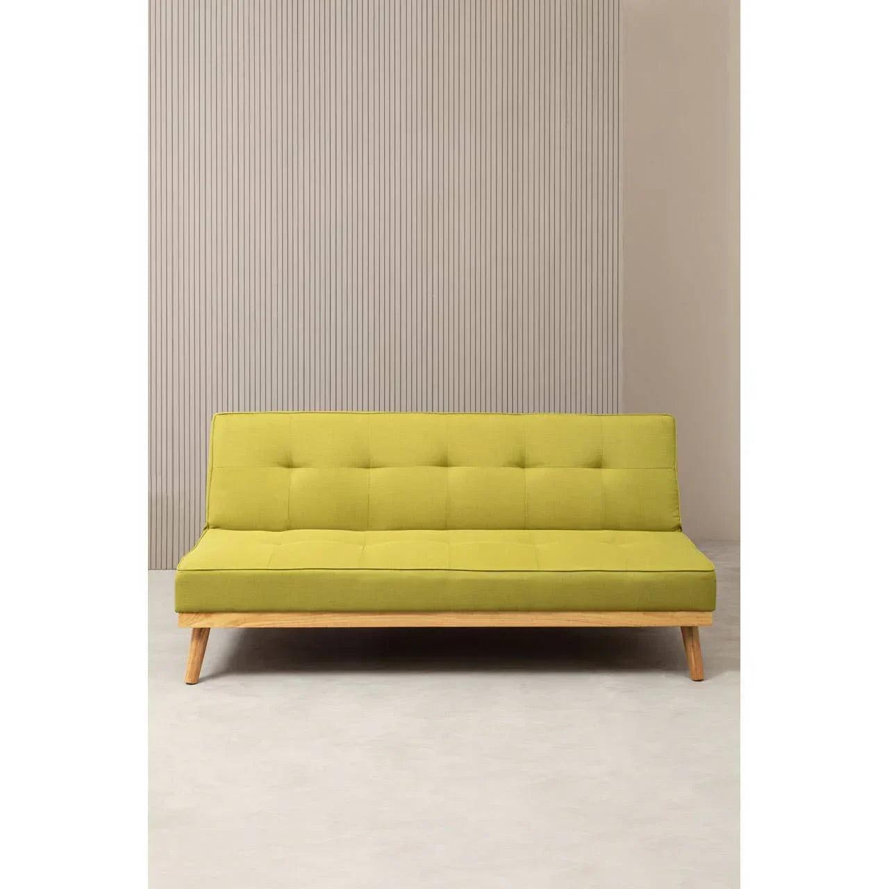 Green modern sofa bed with wooden legs on light flooring against vertical stripe wall backdrop
