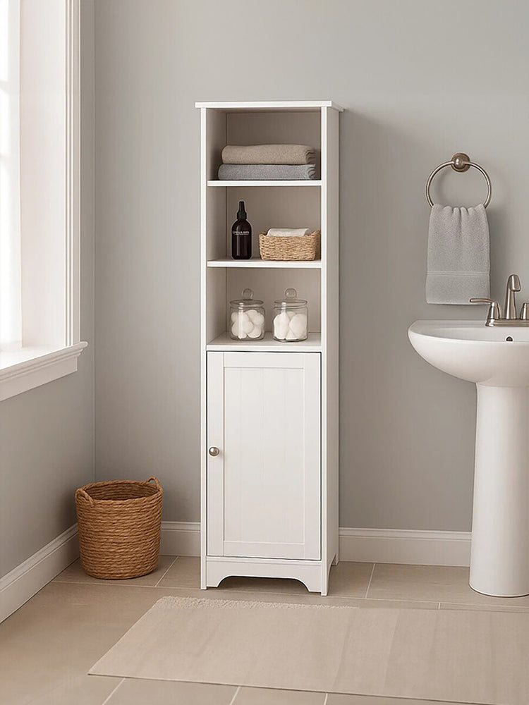 White single door cabinet with three open shelves and a closed bottom section, placed next to a sink in a light-colored room. A woven basket is visible on the floor, and a towel holder is mounted on the wall nearby