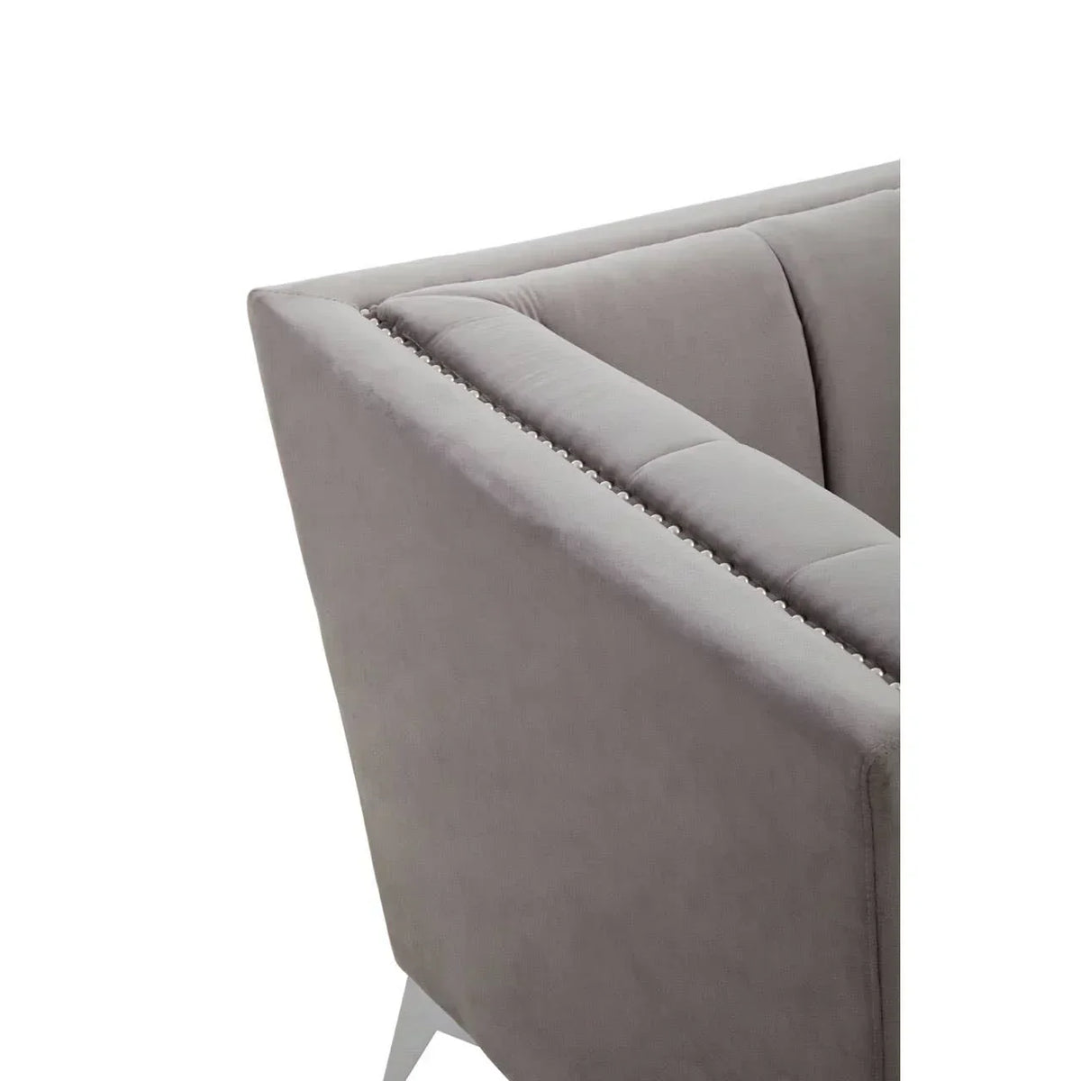 Closeup of grey velvet sofa with silver stud detailing on backrest and angled metal leg