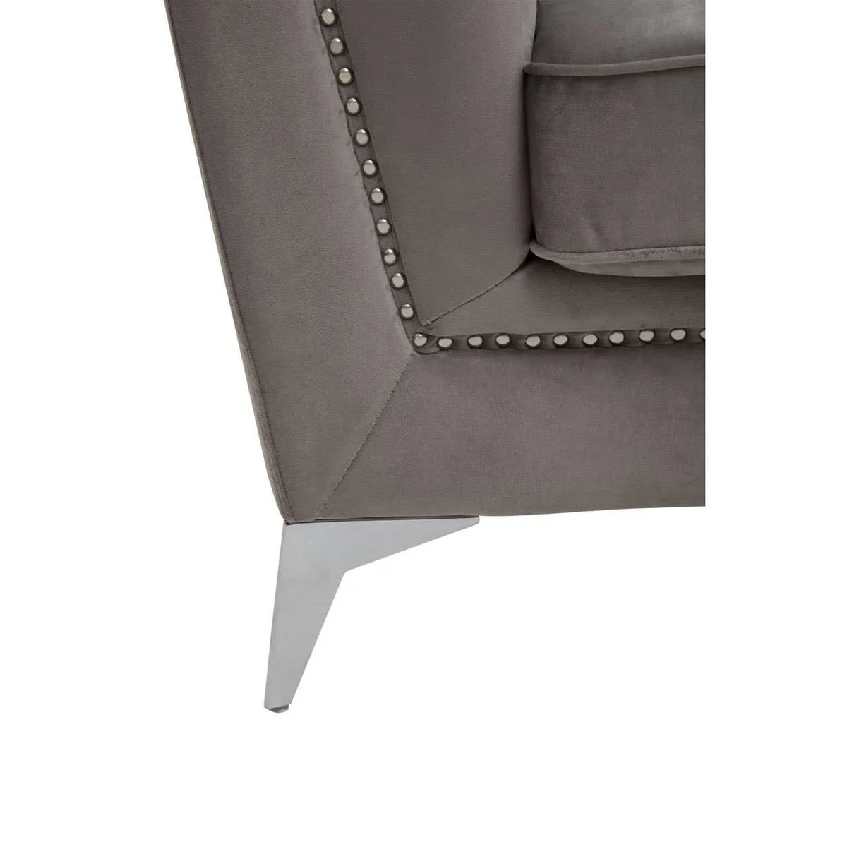 Closeup of grey velvet sofa corner with metal leg and studded trim
