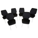 Wimslow black tempered glass dining table accompanied by six sleek black chairs with modern design and metal legs, arranged around the table. The table features a smooth glass surface, reflecting light, while the chairs have a minimalist aesthetic with curved backs