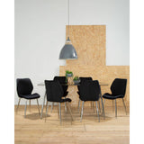 Black tempered glass dining table surrounded by six black upholstered chairs on a light wooden floor. A large pendant light hangs above the table, and a textured wooden wall serves as a backdrop