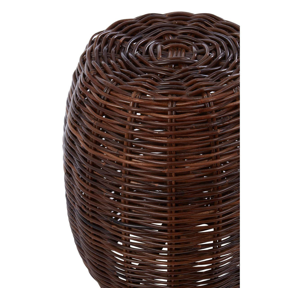 A round stool made from natural rattan, featuring a textured, woven design in dark brown tones. The top has a smooth, rounded edge, and the overall shape is slightly tapered towards the bottom