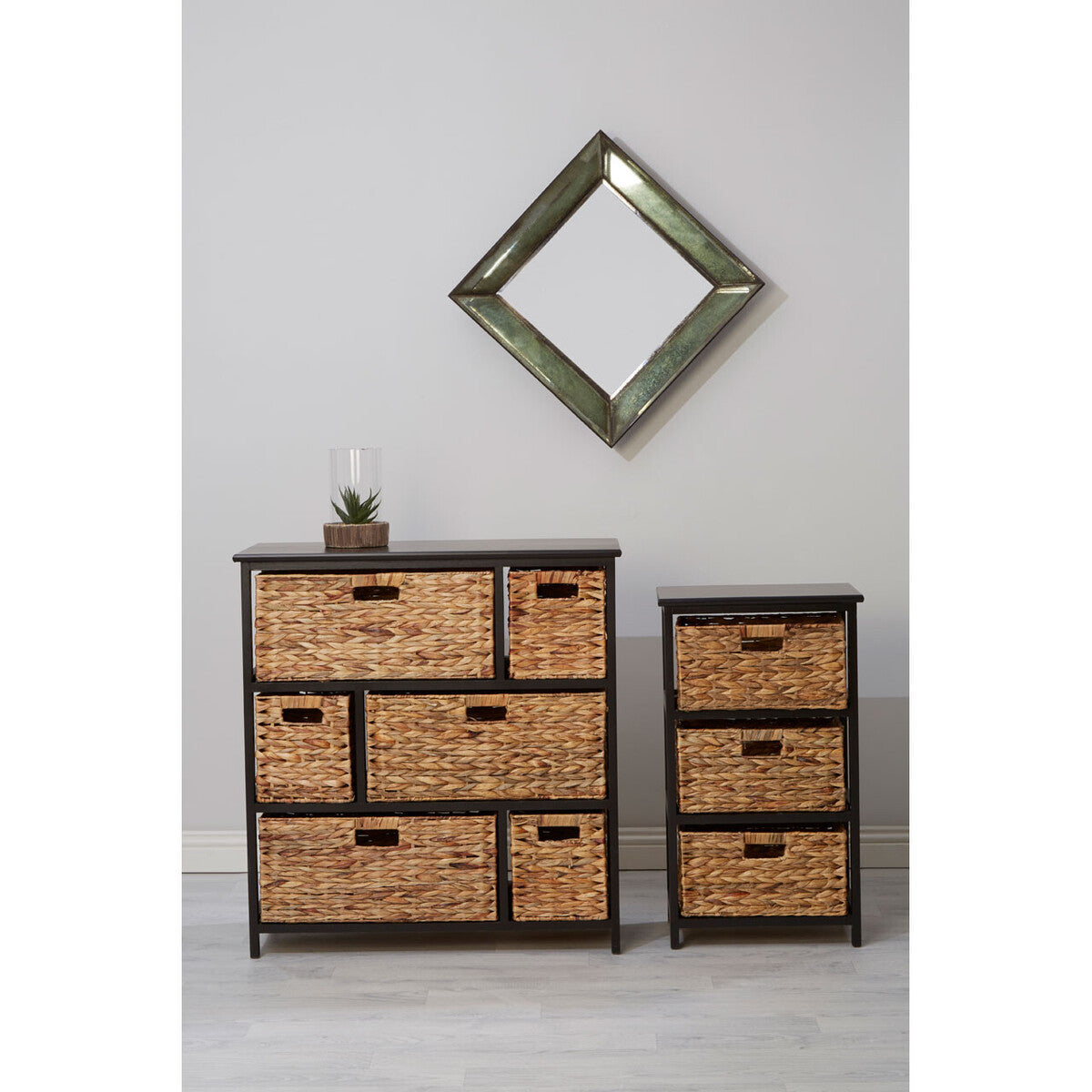 Black storage unit featuring six water hyacinth drawers, arranged in two rows, with a decorative item on top. A small matching unit with three drawers is positioned beside it. A diamond-shaped mirror hangs on the wall above the storage units, set against a light-colored background