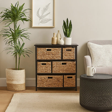 Black storage unit featuring six water hyacinth drawers, placed next to a light-colored sofa and a round coffee table. A potted plant and a framed artwork are visible in the background, enhancing the cozy living space ambiance