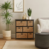 Black storage unit featuring six water hyacinth drawers, placed next to a light-colored sofa and a round coffee table. A potted plant and a framed artwork are visible in the background, enhancing the cozy living space ambiance