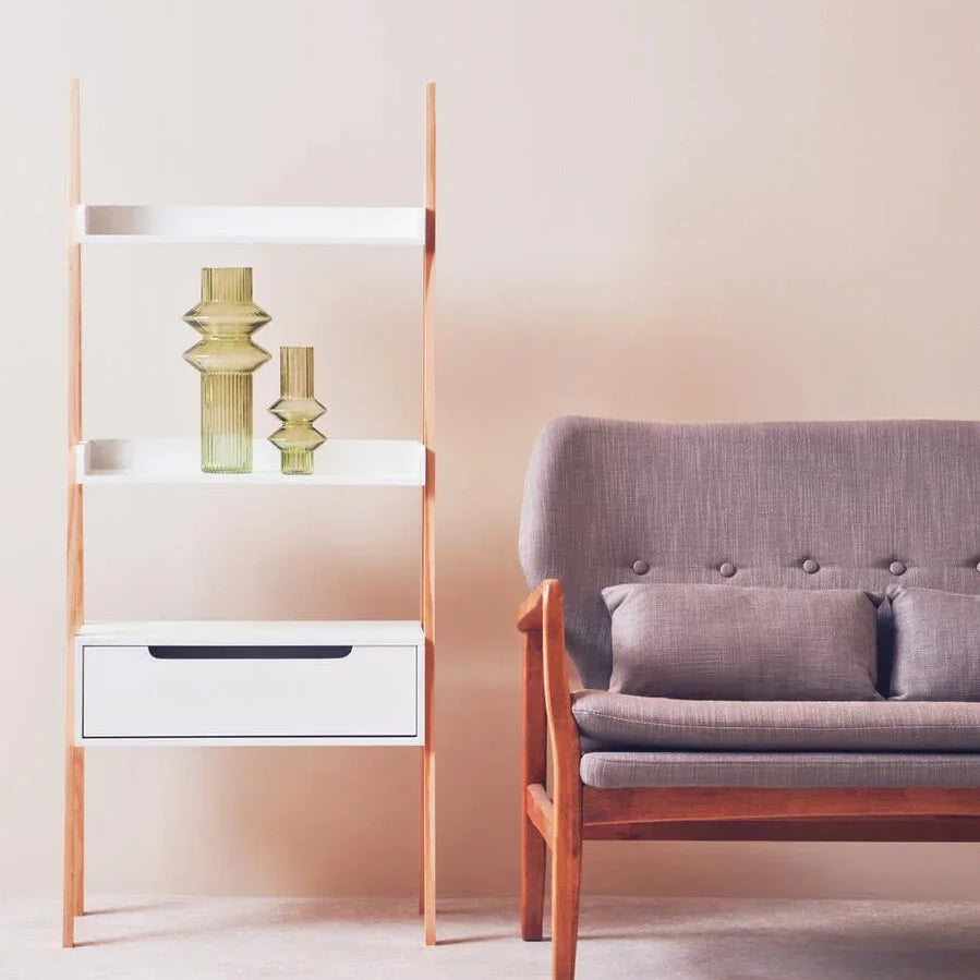 Modern wooden shelving unit with glass vases beside a grey fabric sofa in living room