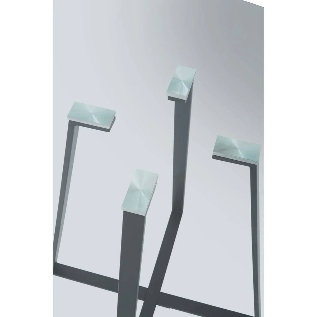 Closeup of brushed metal table legs with square tops against a plain background