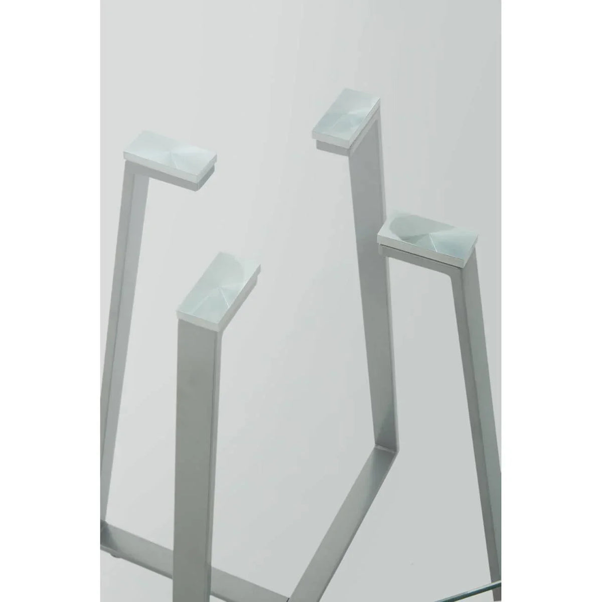 Close-up of modern glass table with silver metal legs and geometric supports