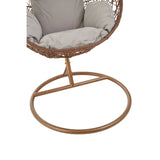 Brown rattan hanging chair with a circular base, featuring a cushioned seat and backrest in a light fabric. The chair has a woven design and is supported by a sturdy metal frame