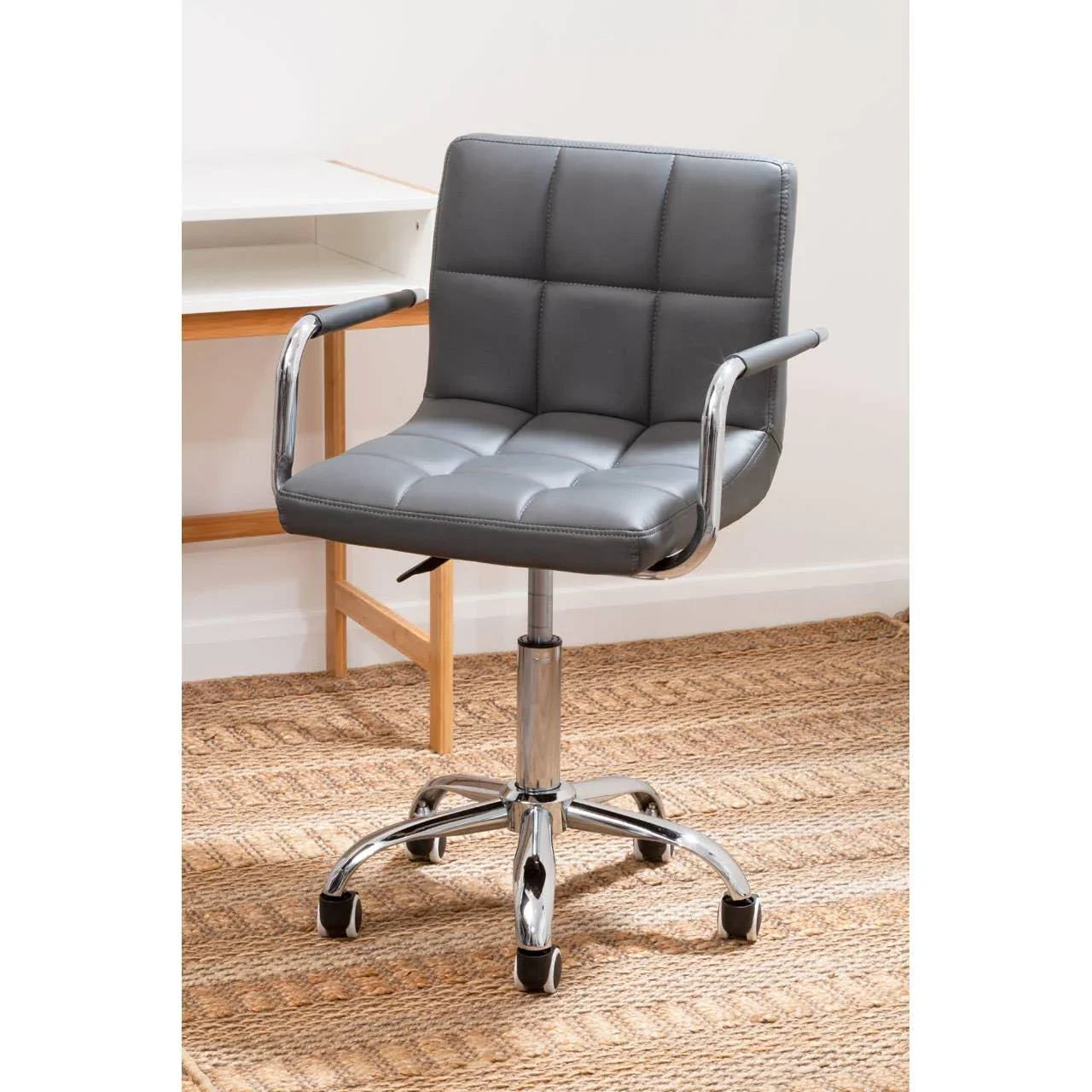Grey leather office chair with chrome base and armrests on woven rug
