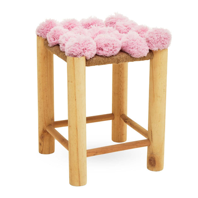 A wooden stool with light-colored legs and a top adorned with fluffy pink pom poms, creating a playful and whimsical design