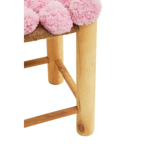 A close-up view of a West Village Pink Pom Pom Stool featuring a soft pink pom pom cushion on top and light wooden legs. The legs are sturdy and rounded, showcasing a natural wood finish
