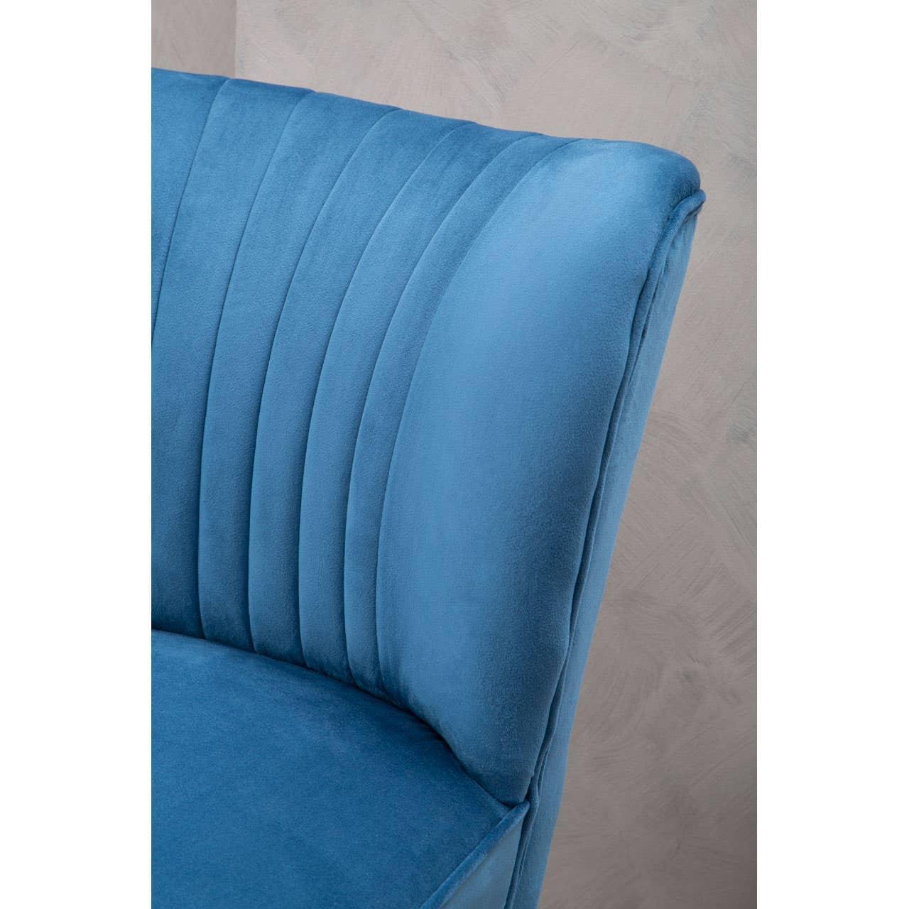 Close up of blue velvet armchair with vertical stitched backrest