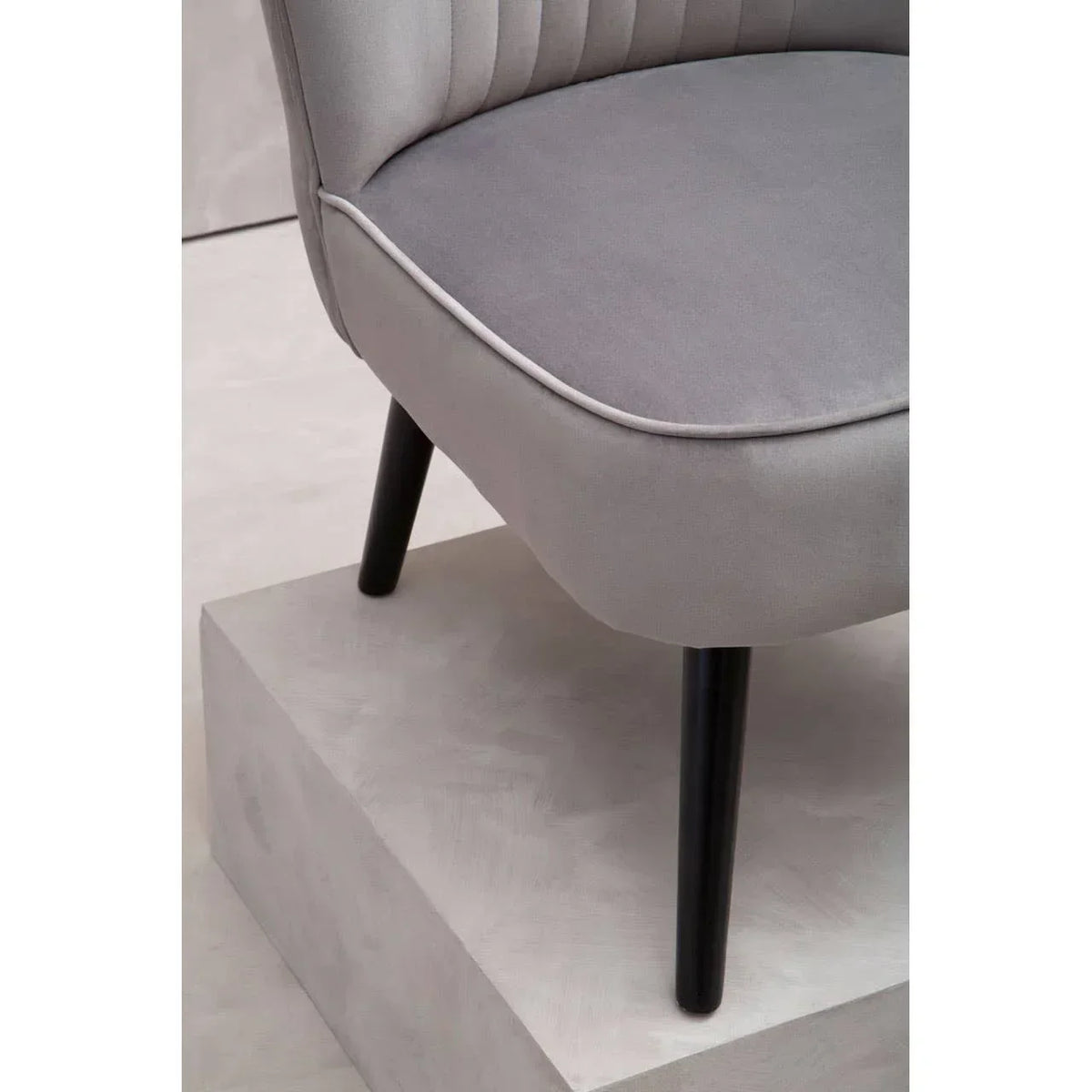 Grey fabric accent chair with black wooden legs and piped edge seat detail