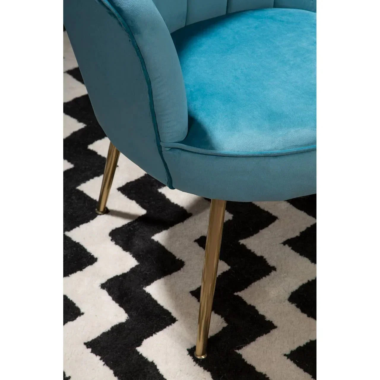 Blue velvet accent chair with gold legs on black and white zigzag rug