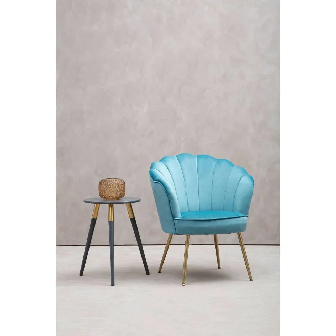 Blue velvet accent chair with gold legs beside round side table and decorative ornament