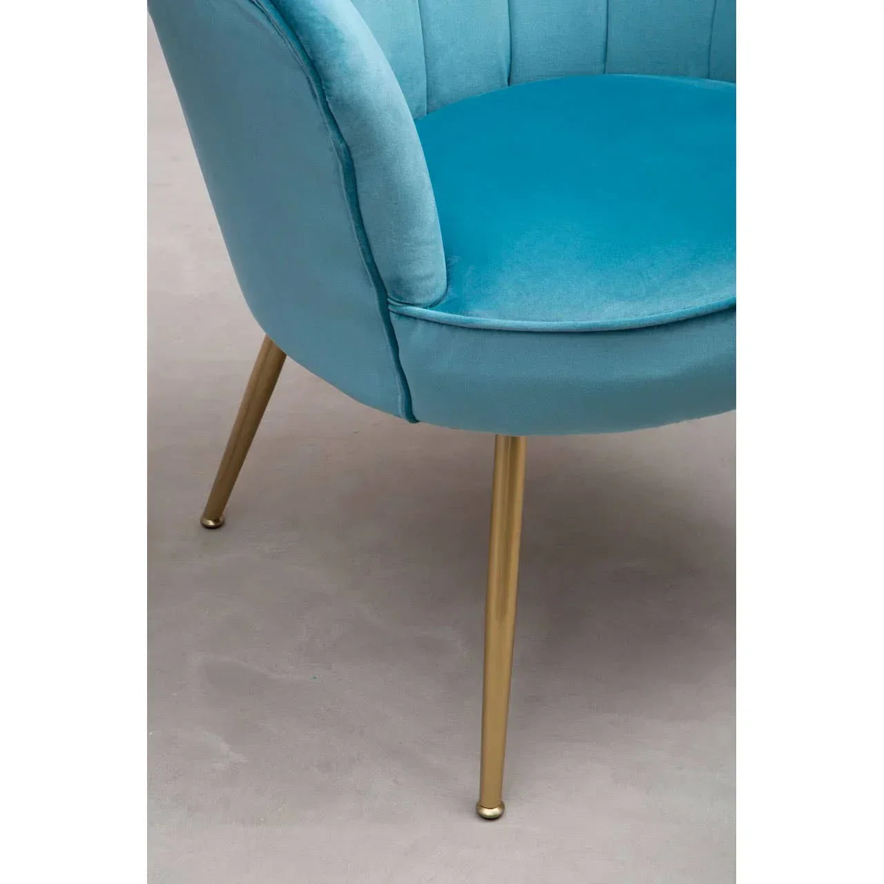 Blue velvet accent chair with gold metal legs, close-up of curved seat and upholstery