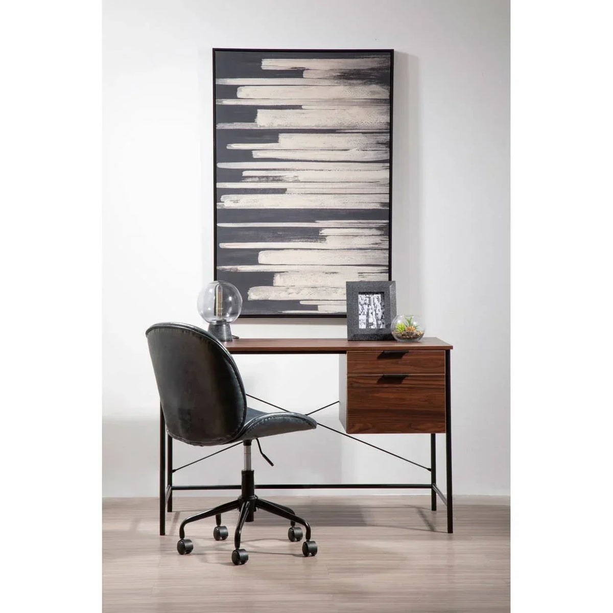 Modern home office desk with black swivel chair and framed abstract wall art