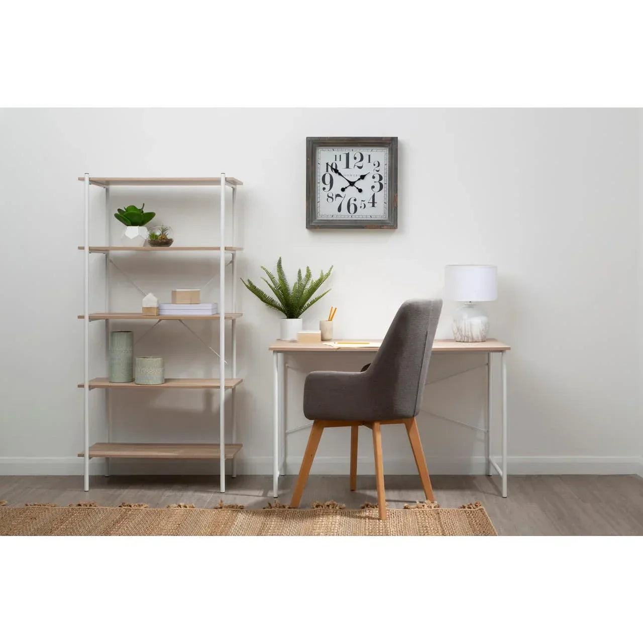 Home office desk with grey chair, shelving unit, and modern decor against white wall