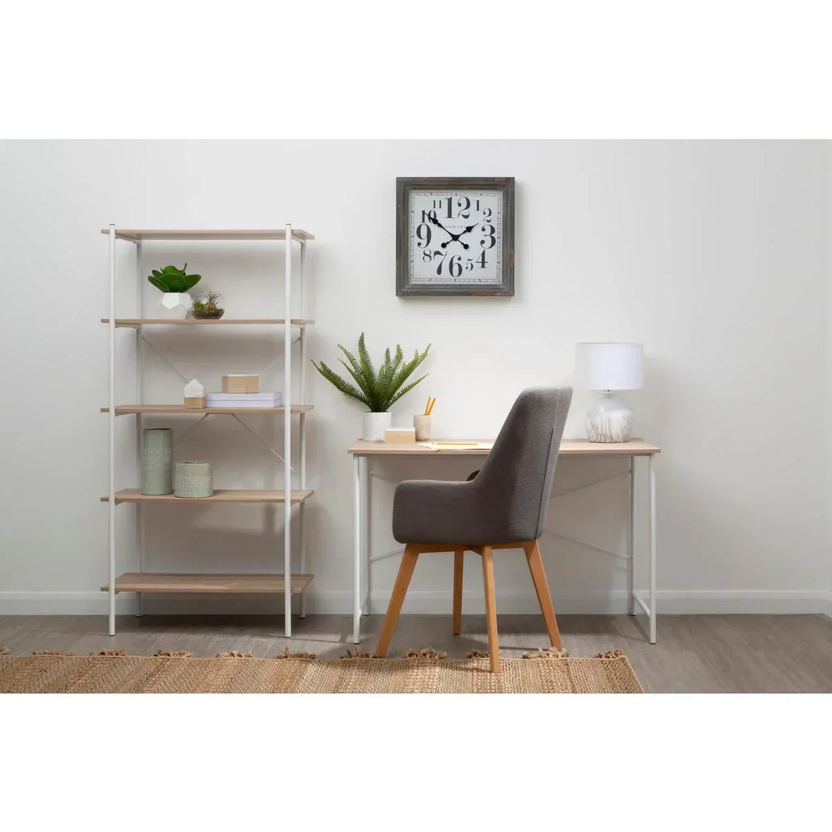Home office desk with grey chair, shelving unit, and modern decor against white wall