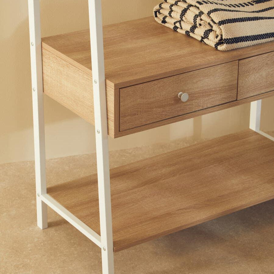 Oak effect shelving unit with white metal frame and two drawers, folded striped throws on shelf
