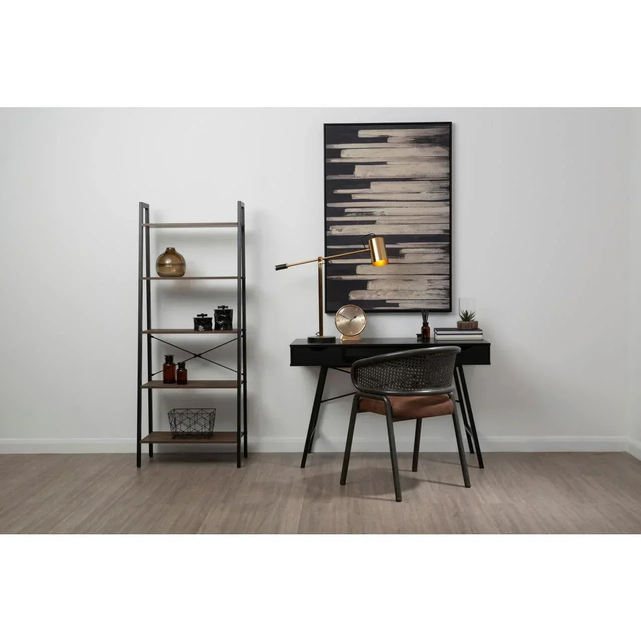 Modern home office desk set with black chair, gold desk lamp, open shelving and abstract art