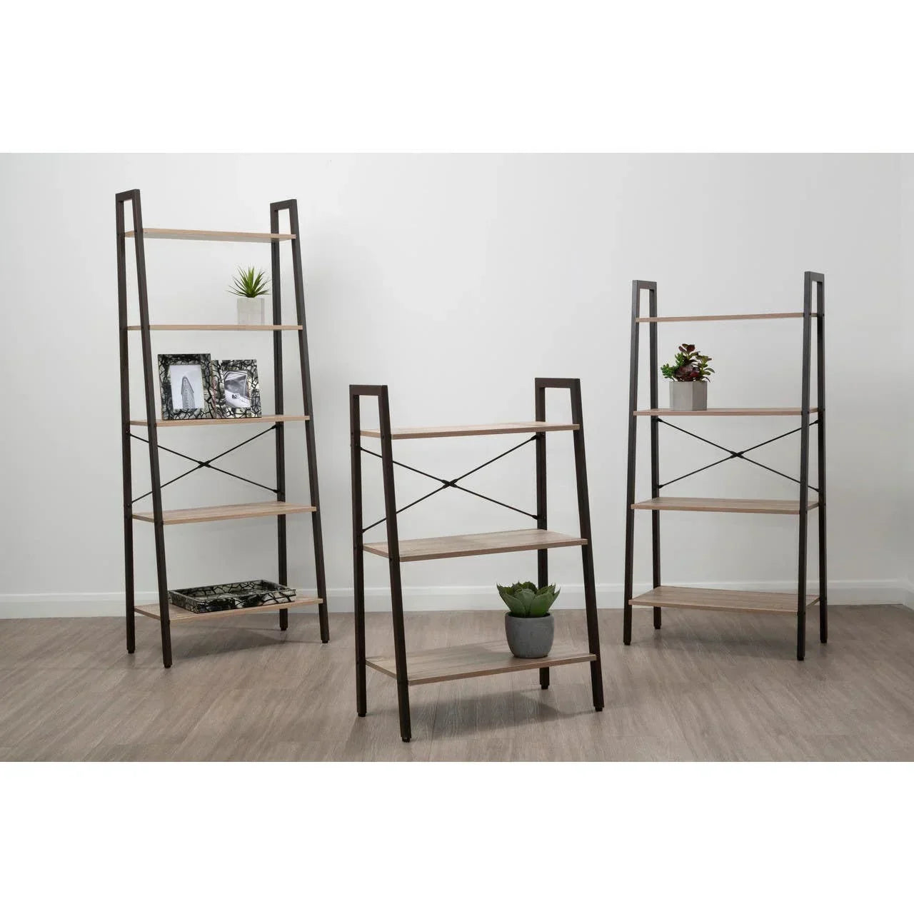 Set of three wood and metal shelving units with decorative plants and photo frames