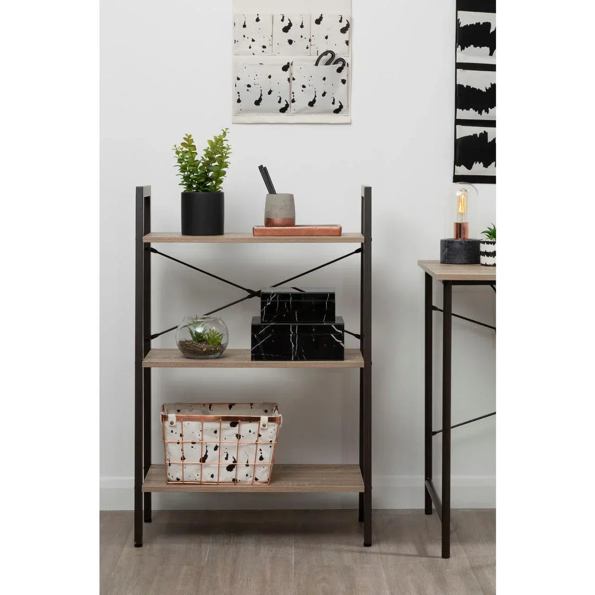 Three tier industrial shelving unit with wood shelves and black metal frame, styled with decor