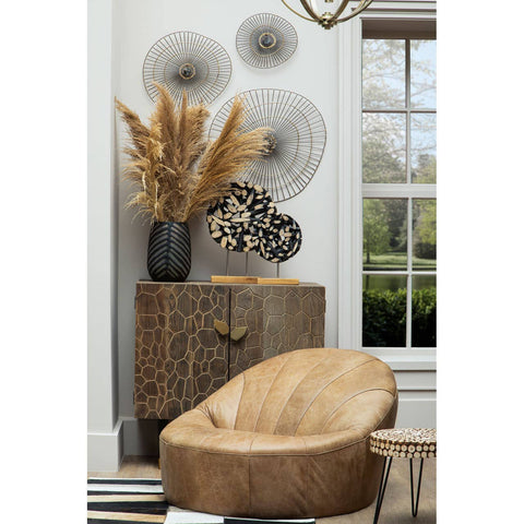 Round side table made of fir wood with a mosaic design, placed next to a textured beige chair. The table features a natural wood finish and is styled with decorative elements, including a black vase filled with dried flowers and wall art in the background