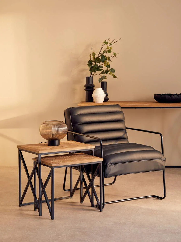 Black leather accent chair with metal frame and nesting side tables in modern living room