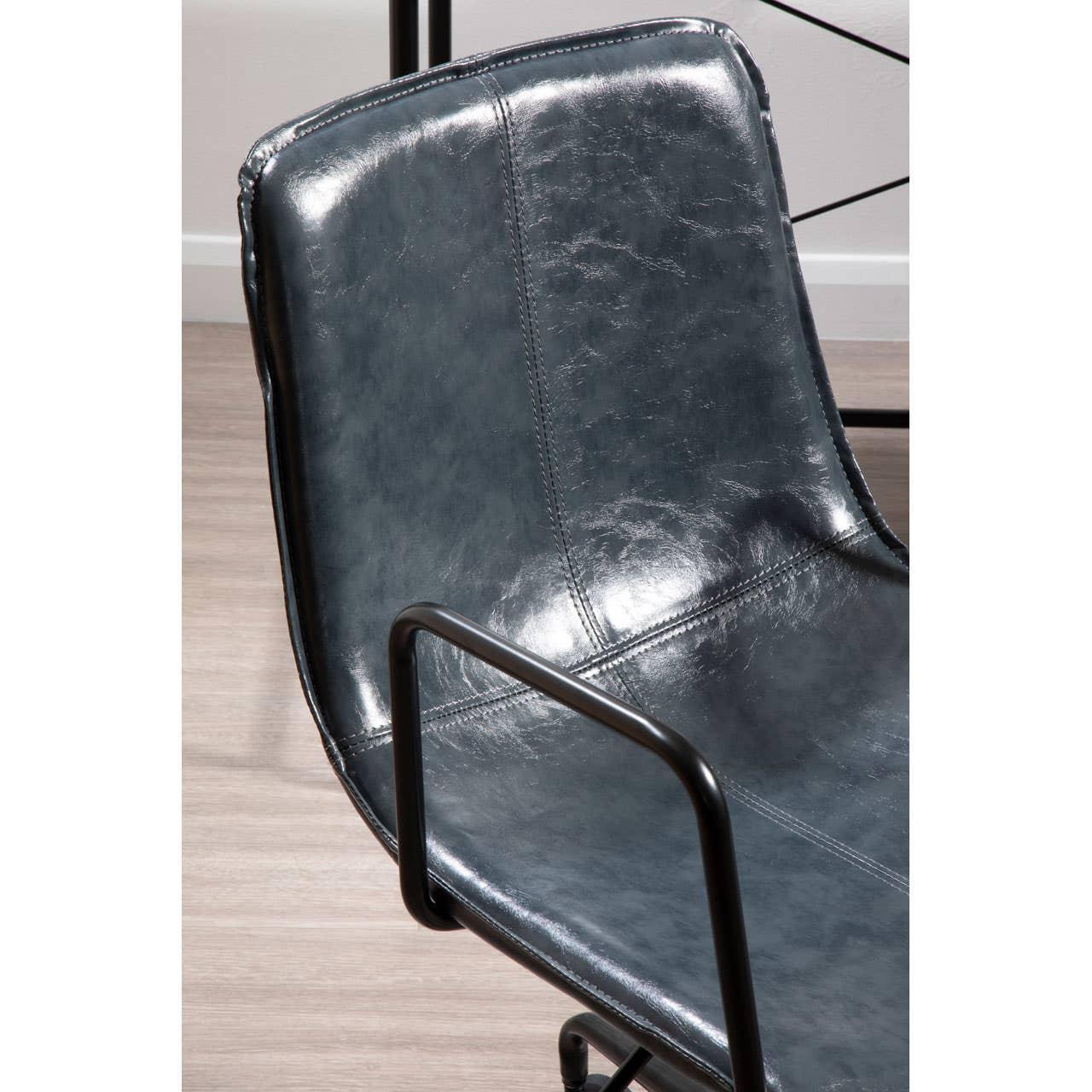 Closeup of black faux leather dining chair with metal armrests and stitched seat detail
