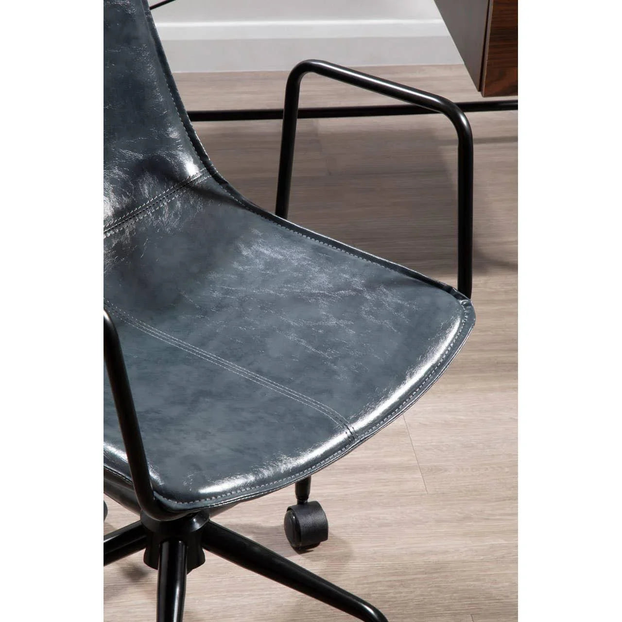 Black faux leather office chair with black metal frame and caster wheels on wood floor