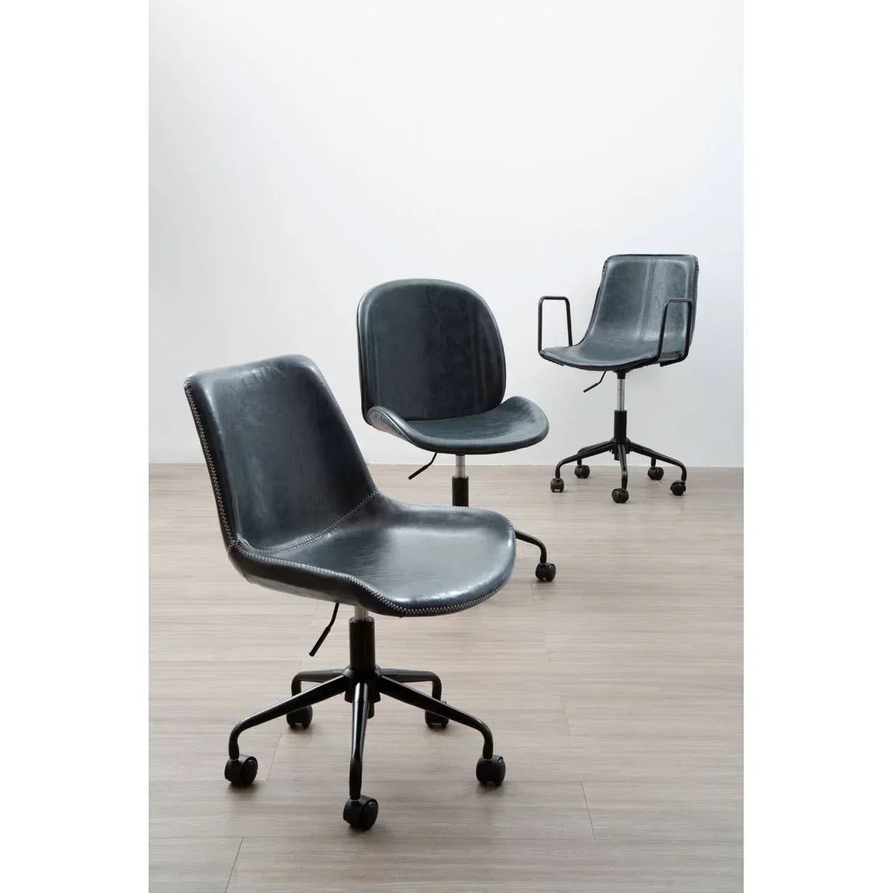 Black leather office chairs with wheels on light wood floor in modern setting