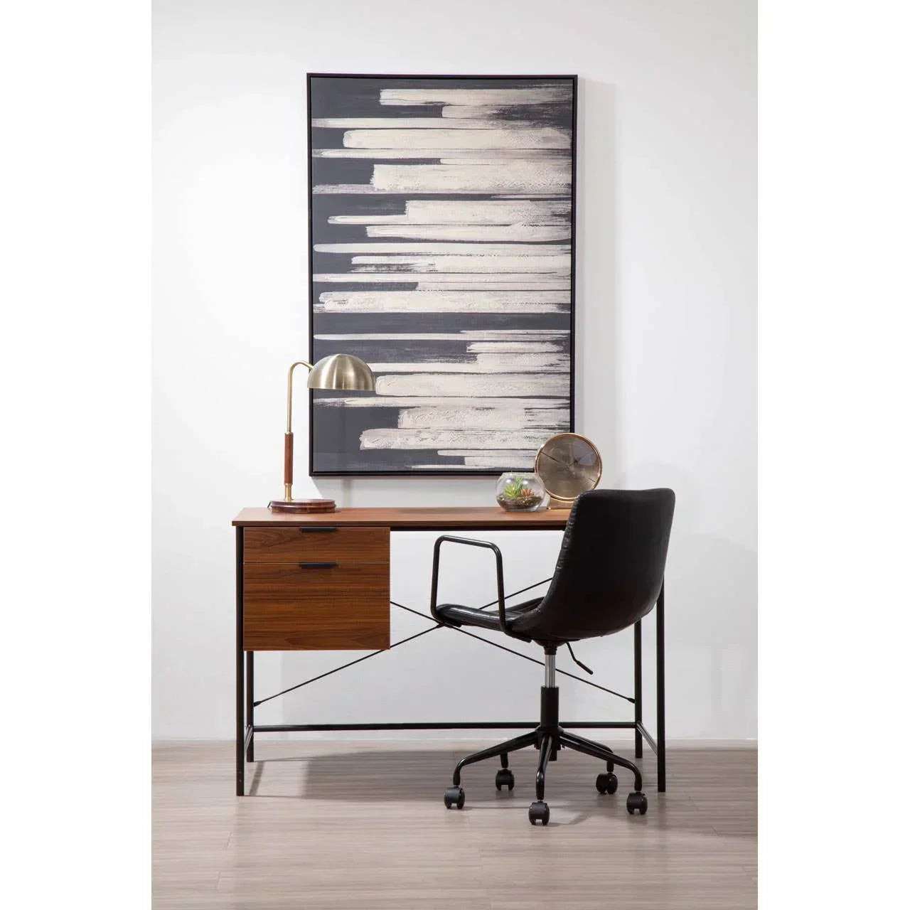 Modern home office desk with wood drawer, black chair, and abstract wall art