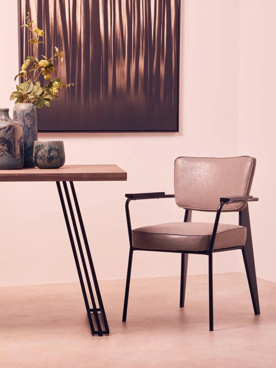 Modern dining chair with faux leather seat and black metal legs beside wooden table