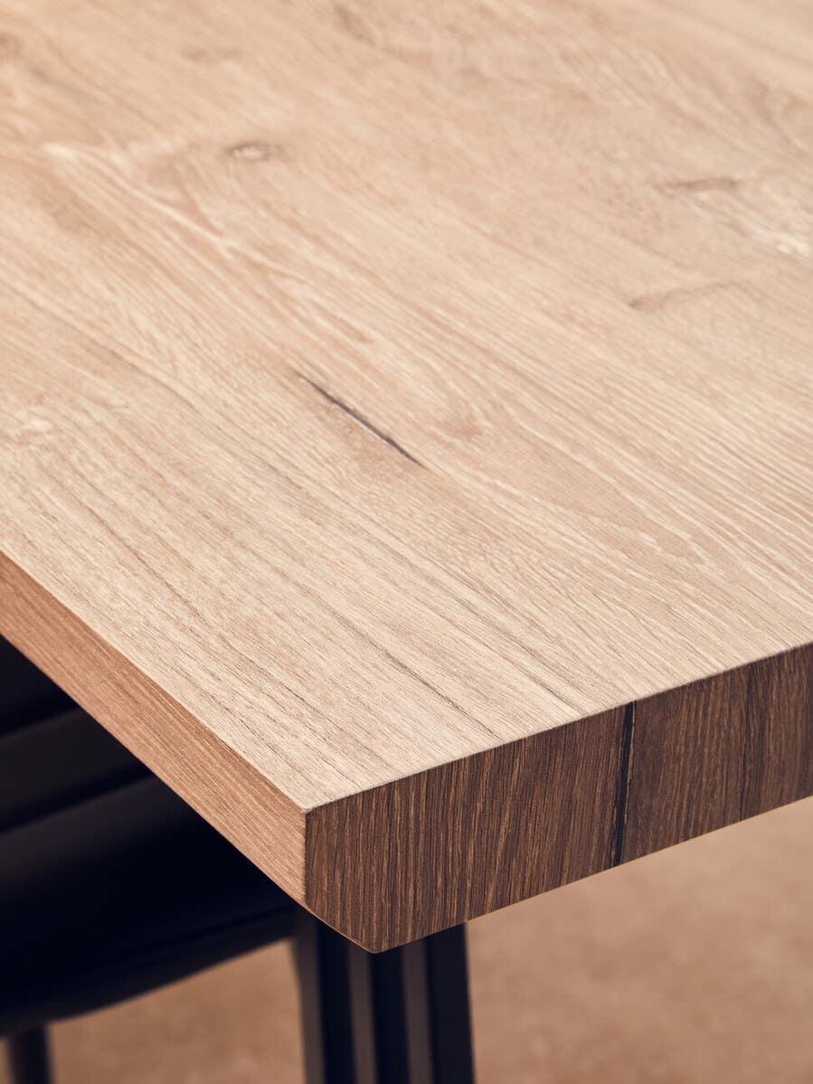 Oak effect dining table with black metal legs, close-up of wood grain and corner detail
