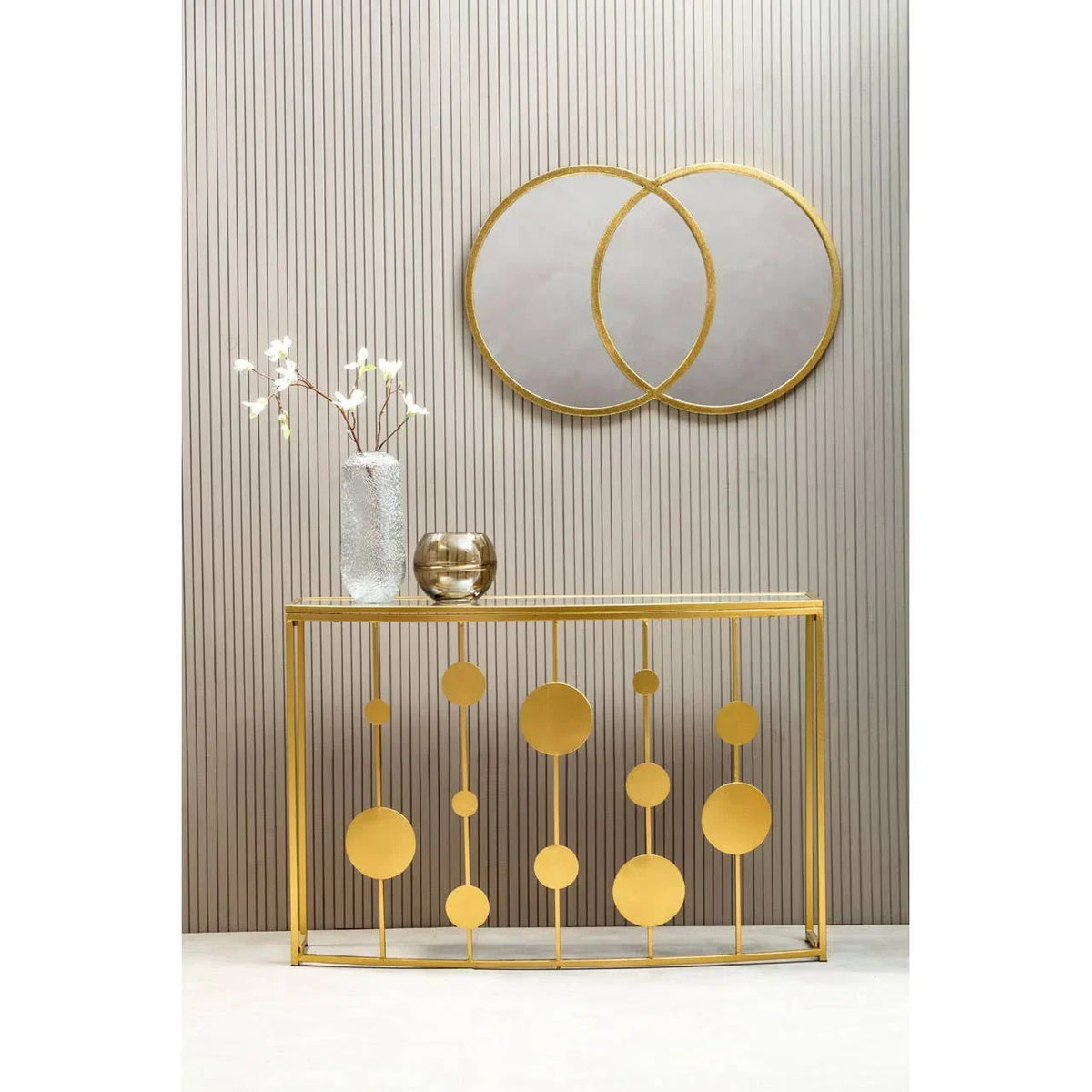 Gold metal console table with geometric circles and decorative vases, wall mirror above