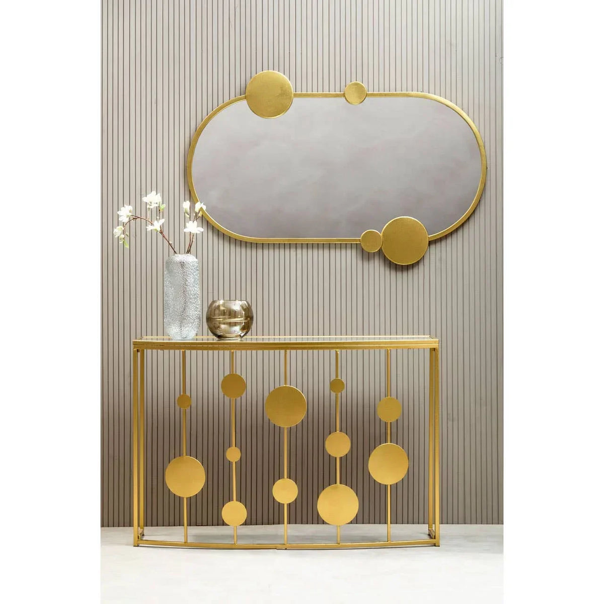 Gold console table with geometric circles and matching gold oval wall mirror in hallway setting