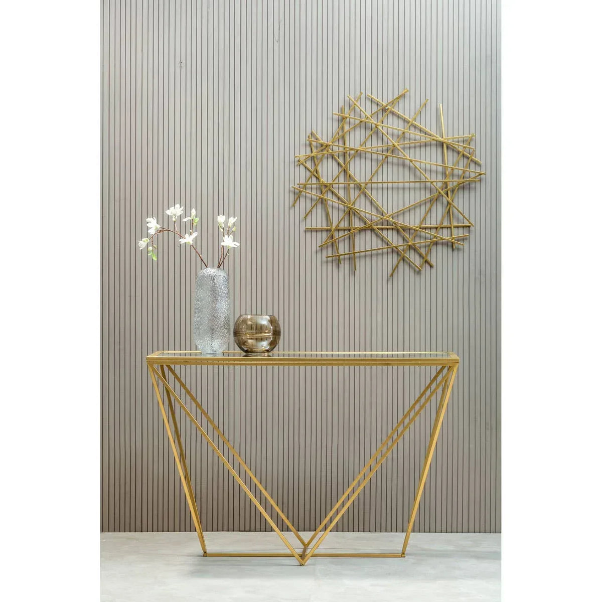 Gold metal console table with glass top, decorative vase and bowl, geometric wall art