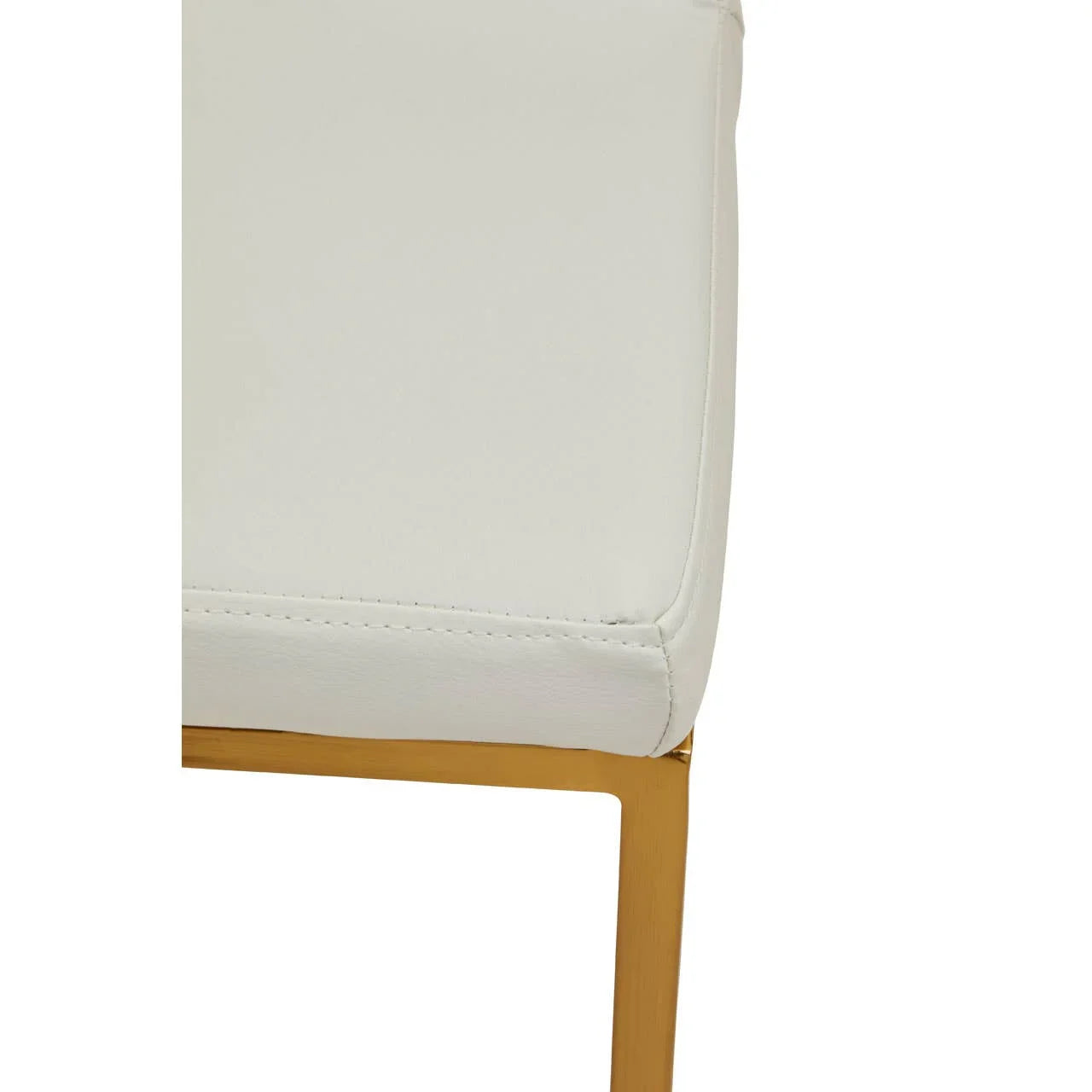 Close-up of white upholstered dining chair seat with gold metal leg detail